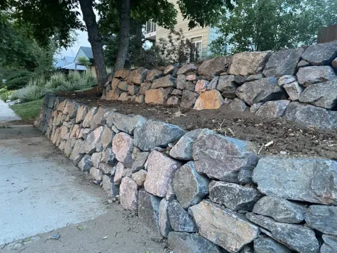 Dry stone retaining wall preventing erosion on a sloped yard